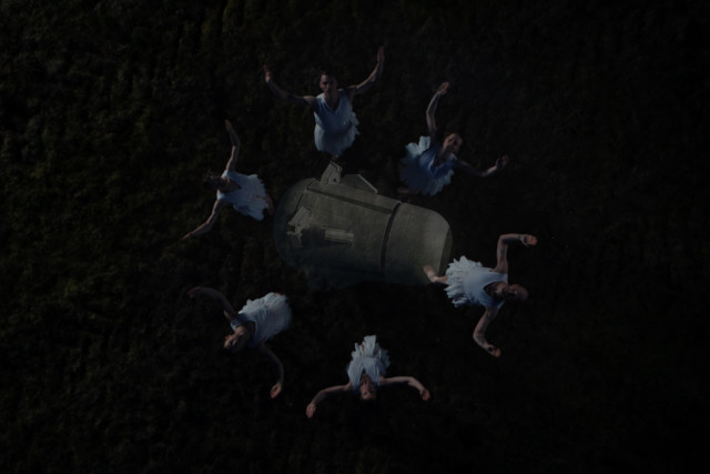 Junge Frauen in weißen Kleidern formen einen Kreis um ein Raumschiff